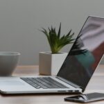 silver laptop and white cup on table